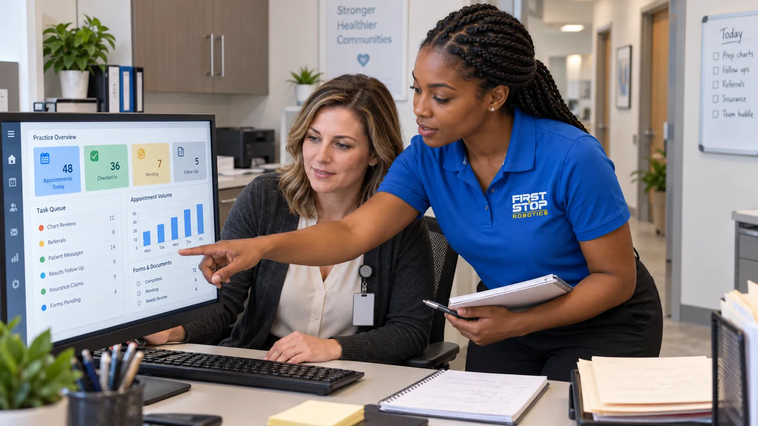 A practice manager at her screen with the appointment list and task queue, a First Stop consultant pointing at it with a notebook, the front desk behind, no patient in frame